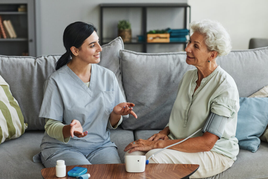 Femal home health aid talking to a patient at home.